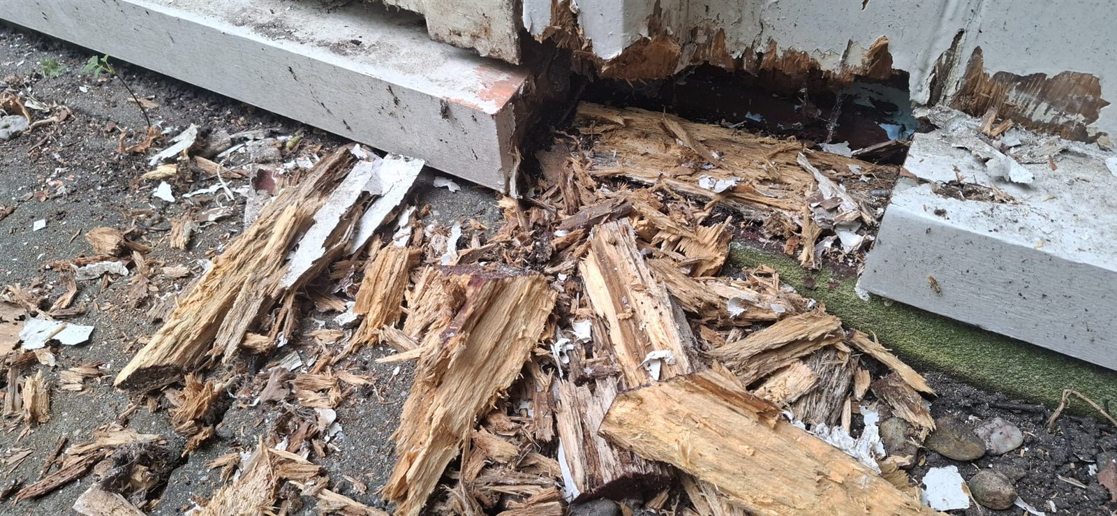 Verrot hout van een onderdorpel, uiteengevallen in splinters op de bestrating