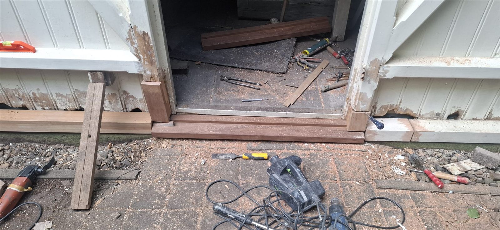 Nieuwe onderdorpel tussen de geopende deuren, gereedschap op de bestrating