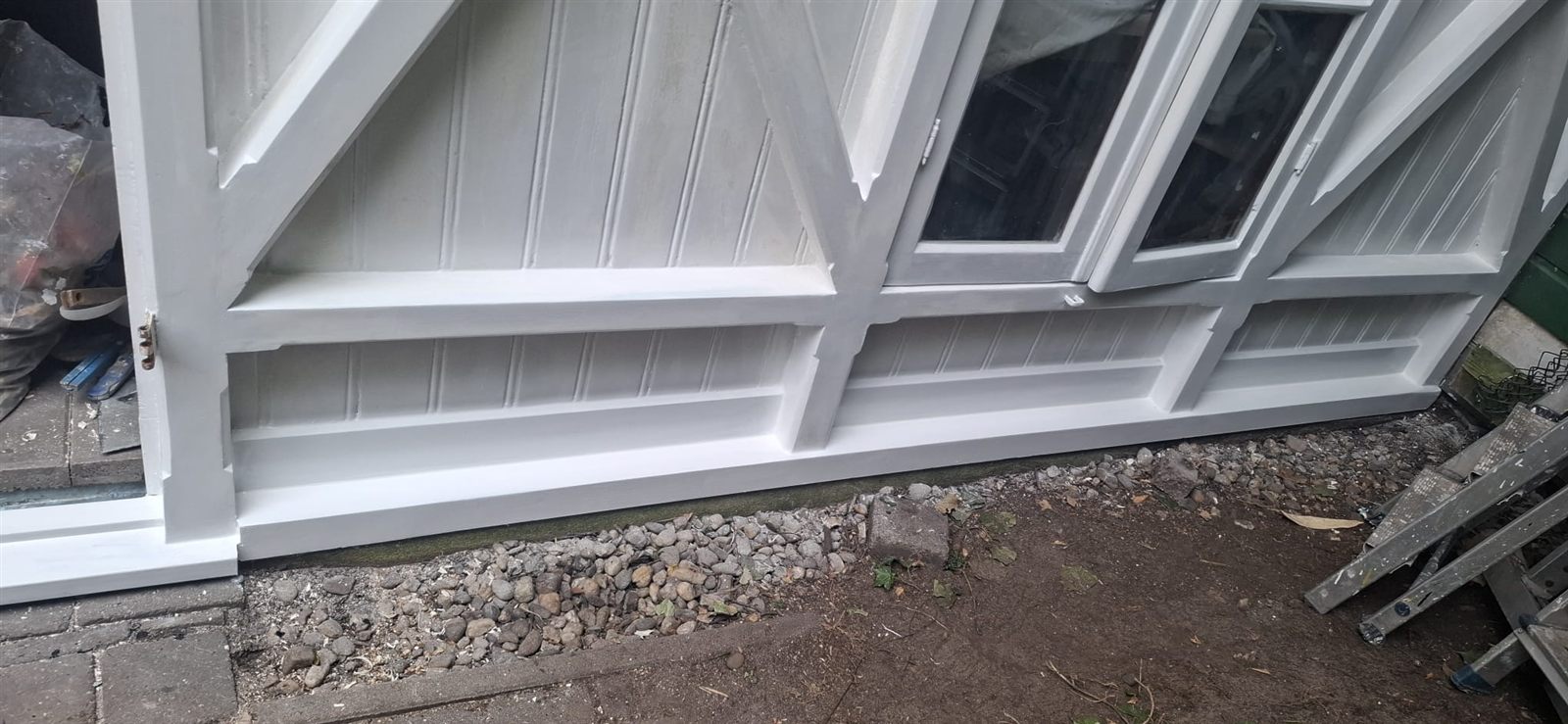 Herstelde deuren en onderregels van het tuinhuis, wit geschilderd